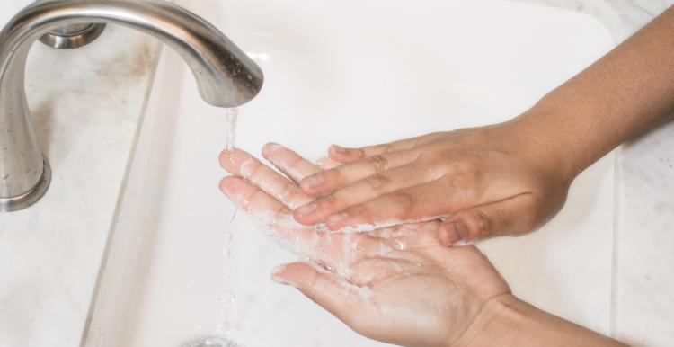 Hands washing over a sink with soap