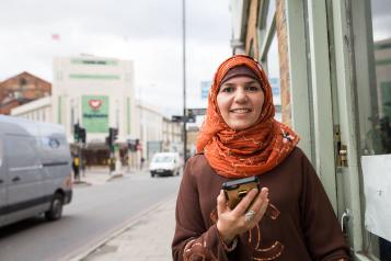 woman standing in the street holding a mobile phone